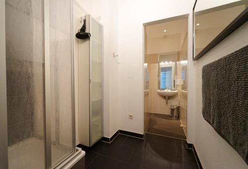 柏林Planet Berlin City Apartments的一间带玻璃淋浴和水槽的浴室