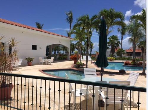 里奥格兰德Rio Mar Village - Golf Course View的阳台设有游泳池、桌子和遮阳伞。