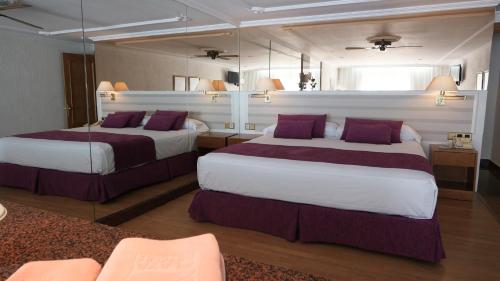 滨海罗克塔斯Playacapricho的酒店客房配有两张带紫色枕头的床