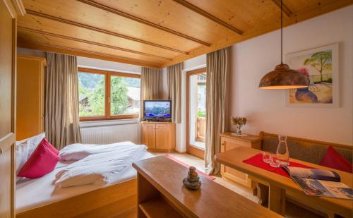 迈尔霍芬兰德豪斯加塞酒店的一间卧室配有一张床、一张桌子和一台电视。