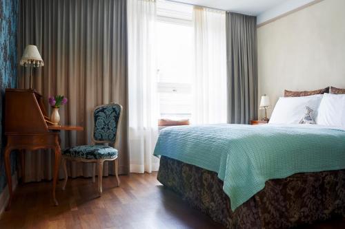 苏黎世市政厅精品酒店的一间卧室配有一张床、一张书桌和一个窗户。
