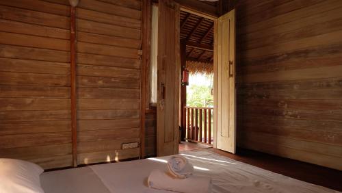 吉利阿尔博兰达生态旅舍的一间卧室设有木墙和一张带窗户的床