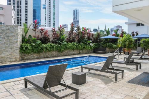 巴拿马城行政酒店的一座带椅子的庭院和一座位于大楼内的游泳池