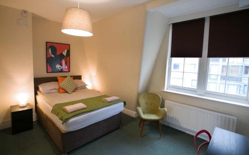 伦敦格兰奇酒吧旅馆的卧室配有床、椅子和窗户。