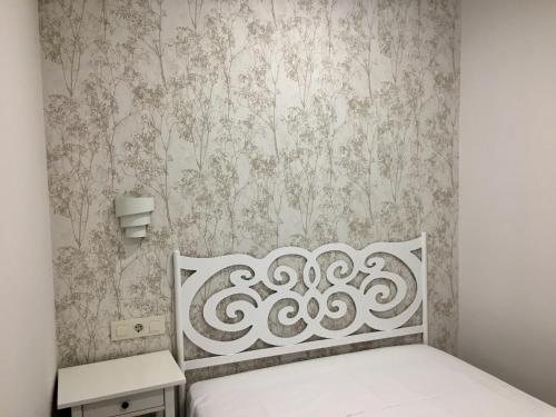 哈兰迪雅·德·拉·维尔APARTAMENTO SAN MIGUEL N.2的卧室配有白色的床和壁纸