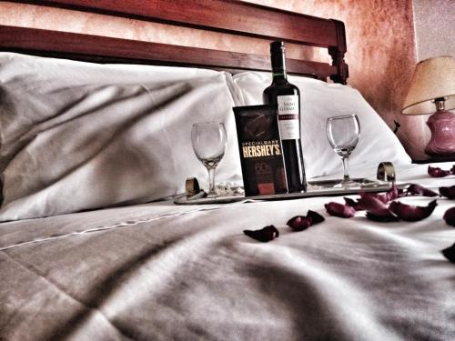 卡曼杜卡亚Pousada das Palmeiras的床上有一瓶葡萄酒和两杯酒