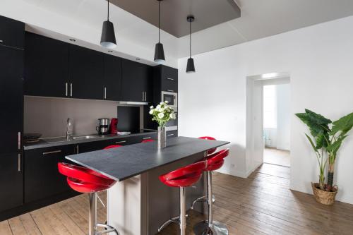圣马洛Zen et design, proche Cité Corsaire的厨房配有黑色橱柜和红色吧台凳