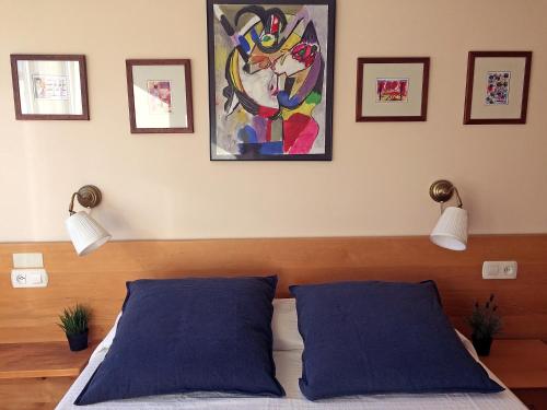 Añorga-LugarizVT Musikene Parking ESS01579的卧室配有2个蓝色枕头,墙上挂有绘画作品