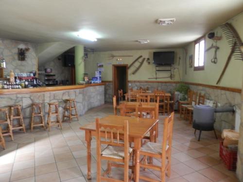 Linares de MoraHostal El Portalico的一间带木桌椅的餐厅和一间酒吧