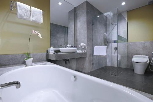 马塔兰ASTON Inn Mataram的带浴缸、水槽和淋浴的浴室