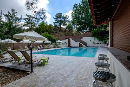 普拉特斯Platres Valley Houses的游泳池旁的游泳池配有椅子和遮阳伞