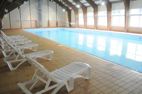 Les MoussièresVillage Vacances Passion Georges Moustaki的旁边设有白色躺椅的大型游泳池