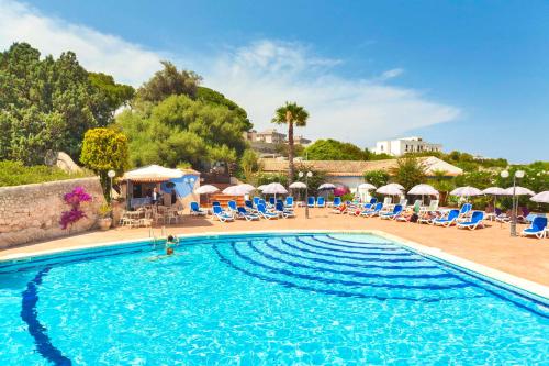 锡拉库扎波利蒂别墅大酒店的度假村的游泳池,配有椅子和遮阳伞