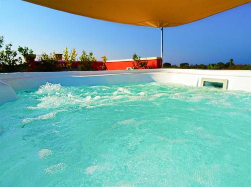 加利波利萨兰托加里波利比安库利沃住宿加早餐旅馆的一个带遮阳伞的大型蓝色海水游泳池
