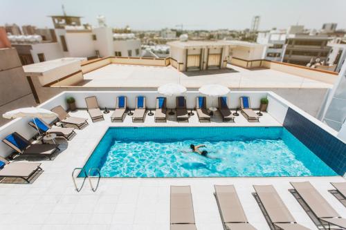 拉纳卡弗兰吉奥酒店的在建筑物顶部的游泳池游泳的人