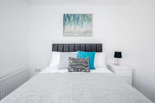 阿克斯桥Elthorne Luxury Apartments - Uxbridge的白色卧室配有一张带蓝色枕头的大床