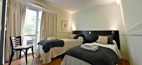 门多萨四月精品酒店的客房设有两张床、一把椅子和窗户。