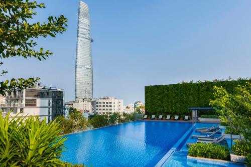 胡志明市Sedona Suites Ho Chi Minh City的一座游泳池,其背后是一座高大的建筑