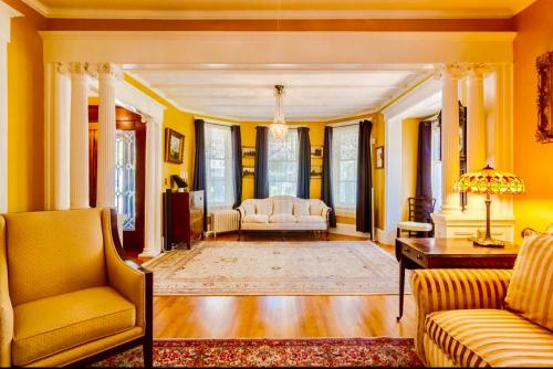 加纳诺克1000 Islands Bed and Breakfast-The Bulloch House的客厅设有黄色的墙壁、一张沙发和一张桌子