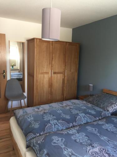 滕宁Hafenperle的一间卧室配有蓝色的床和木制橱柜