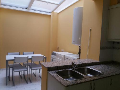 格罗韦Apartamento de dos plantas en Rúa Platería的厨房配有水槽和桌椅
