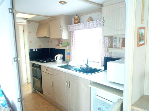 索博特卡Ubytovani v mobilnim domku的厨房配有白色橱柜、水槽和窗户。