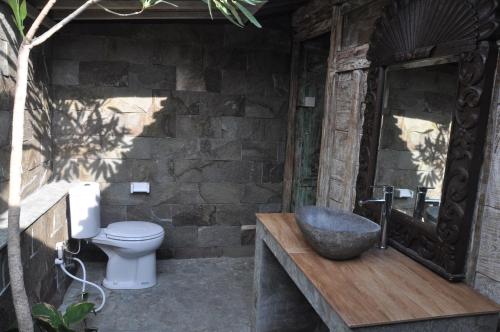 坎古库布迪尤玛巴厘岛别墅的一间带卫生间和石墙的浴室