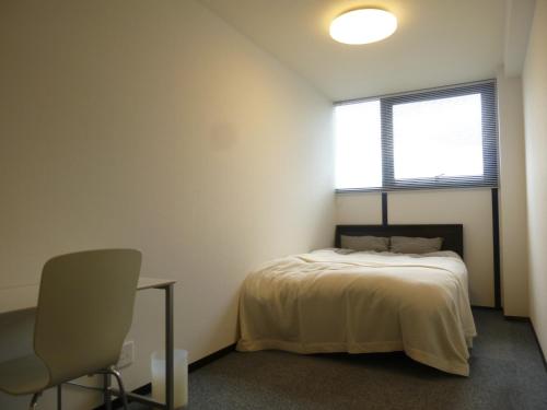 名古屋Nagoya Motoyama House D的卧室配有床、椅子和窗户。