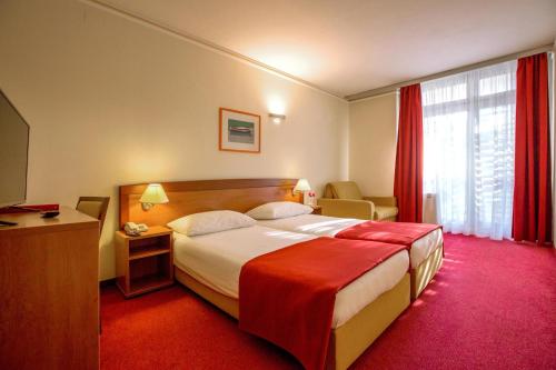 希贝尼克Amadria Park Beach Hotel Niko的酒店客房,配有一张铺有红地毯的大床