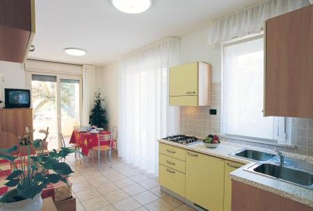 阿尔巴·阿德里亚蒂卡Residence Le Palme的一间带黄色橱柜的厨房和一间带桌子的用餐室