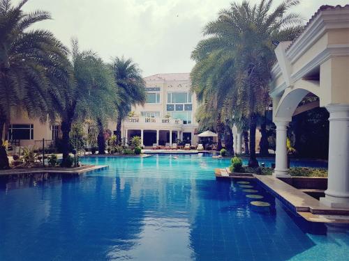古尔冈The Palms Town & Country Club - Resort的一座楼前棕榈树游泳池