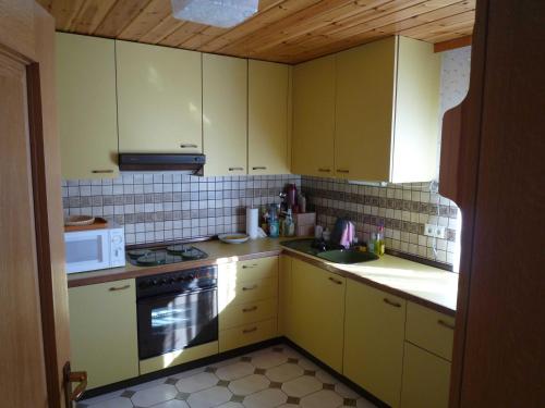 福森FeWo Ortloff的厨房配有黄色橱柜、炉灶和微波炉。