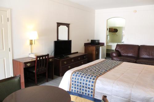 麦卡伦Texas Inn Downtown McAllen的酒店客房配有床、沙发和电视。
