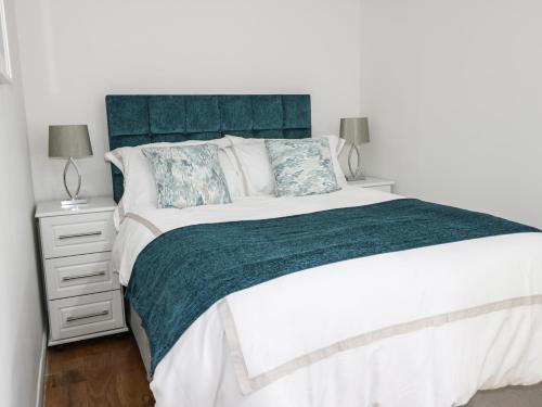 特维德上游的贝里克6 Mill Wharf的一间卧室配有一张大床和蓝色床头板