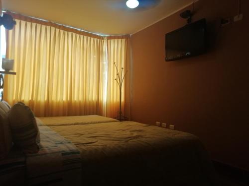 齐克拉约Hospedaje Oasis的一间卧室设有一张床和一个带电视的窗户。