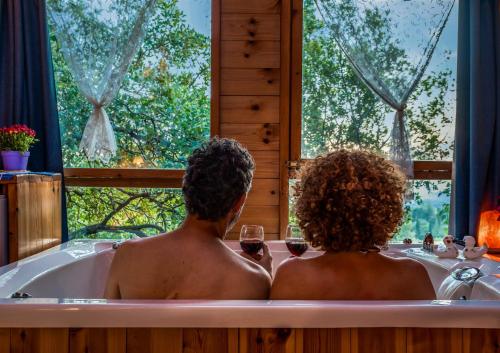 埃米瑞姆树林中的Spa - 阿米灵住宿加早餐旅馆的两人坐在浴缸里,喝一杯葡萄酒