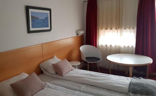 GlomfjordGlomfjord Hotel的一间卧室配有一张床、一张桌子和一个窗户。