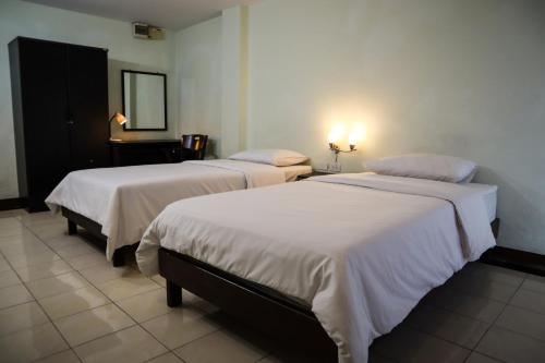 乌隆他尼乌冬卡巴那酒店的配有镜子的酒店客房内的两张床