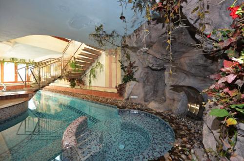 莫埃纳Hotel La Soldanella的游泳池旁设有岩石墙,旁边是游泳池
