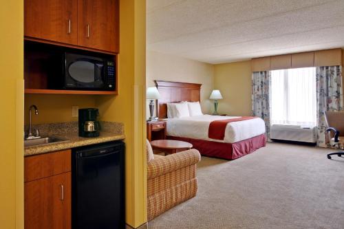 布卢明顿Holiday Inn Express & Suites Bloomington, an IHG Hotel的酒店客房配有一张特大号床和一间厨房。