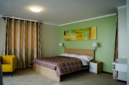 帕拉马里博Gess Hotel的一间卧室配有一张床和一张黄色椅子