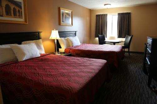 凯尔索Americas Best Value Inn Kelso的酒店客房带两张床和一张桌子以及椅子。