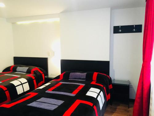 伊皮亚莱斯Hotel San José Ipiales的配有红色窗帘的客房内的两张床