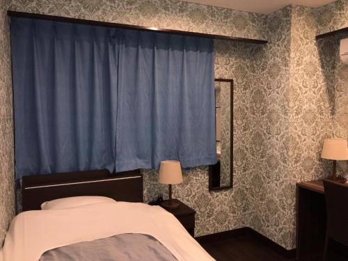 东京哈托娅酒店的一间卧室配有床和蓝色窗帘