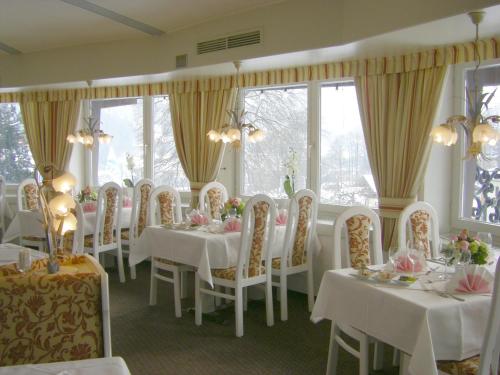贝希特斯加登科隆普林兹酒店的一间设有白色桌椅和窗户的用餐室