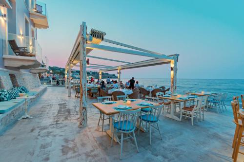 罗希姆诺Thalassa Boutique Hotel的海滩上的餐厅,配有桌椅