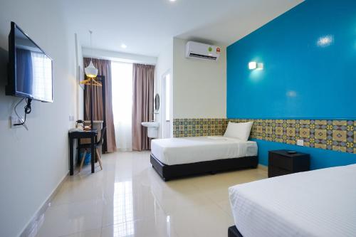 乔治市Grand FC Hotel的酒店客房设有两张床和蓝色的墙壁。