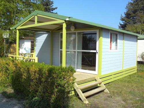 斯特拉海滩松塔露营地的绿色白色的小房子,设有门廊