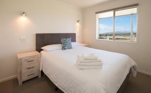 雅纳基普罗姆盖特逍遥度假屋的一间卧室配有一张带白色床单的床和一扇窗户。