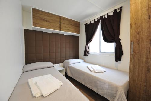 佩斯基耶拉德加达意大利贝拉露营酒店的一间卧室设有两张床和窗户。
